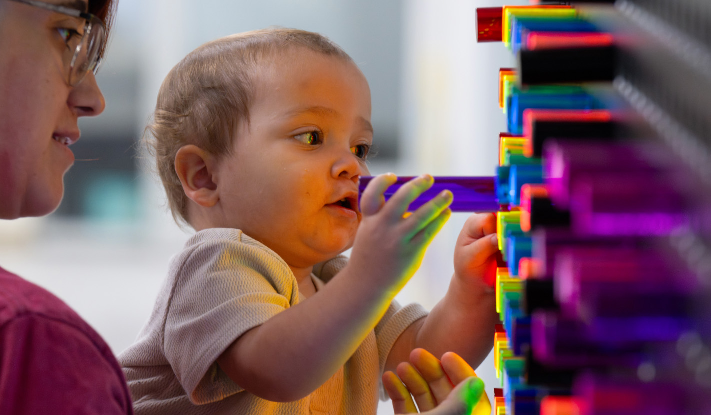 Image of toddler pushing colorful pegs into wall