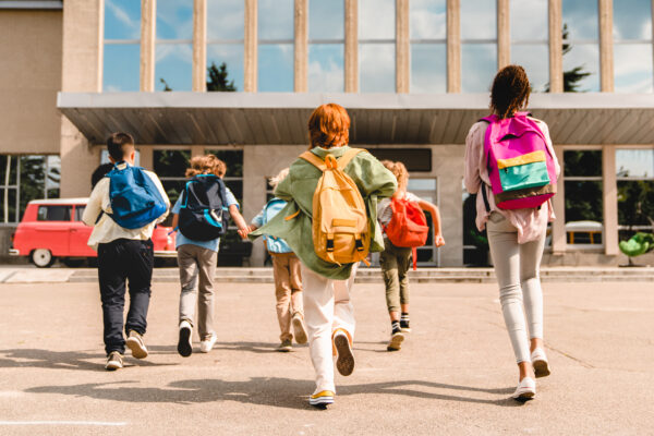Kids with backpacks walking into school 