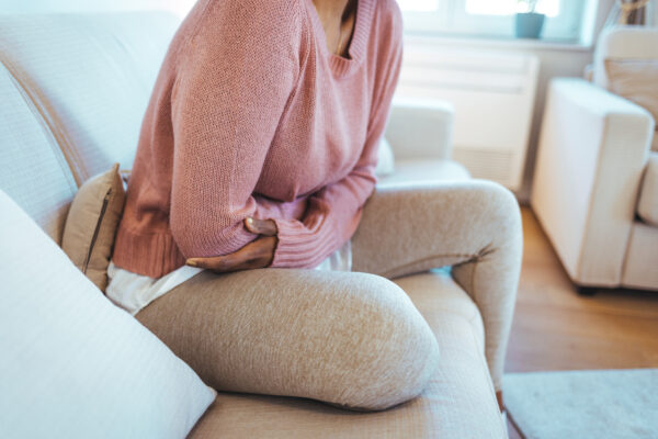 Cropped shot of a young woman sitting down on her couch and suffering from period pains at home.