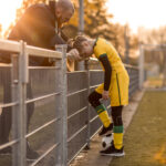 Soccer father coaching football daughter during a game