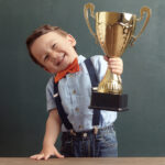Little boy raising a golden trophy