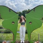 Evelyn Caldwell stands between sculpture of butterfly wings