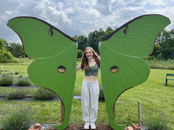 Evelyn Caldwell stands between sculpture of butterfly wings