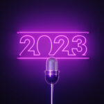 Purple Neon Light Writes 2023 Above A Silver Colored Microphone Over Black Background