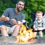 Father and Son Roasting Marshmallow over Campfire in Camping in Summer