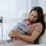 Mother holding her baby boy in the nursery room