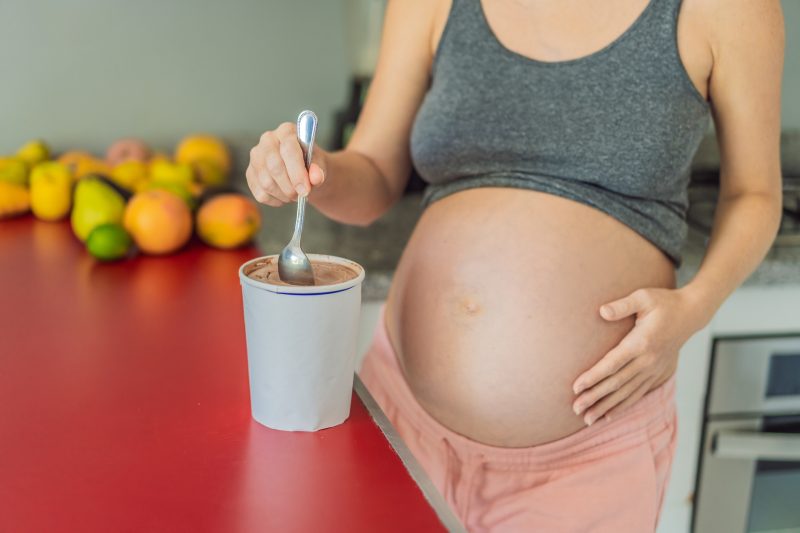 Happy pregnant young woman eating ice cream