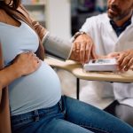 Close up of a doctor measuring pregnant woman's blood pressure.