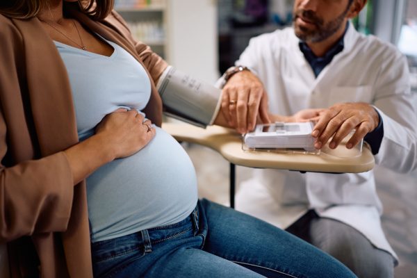 Close up of a doctor measuring pregnant woman's blood pressure.