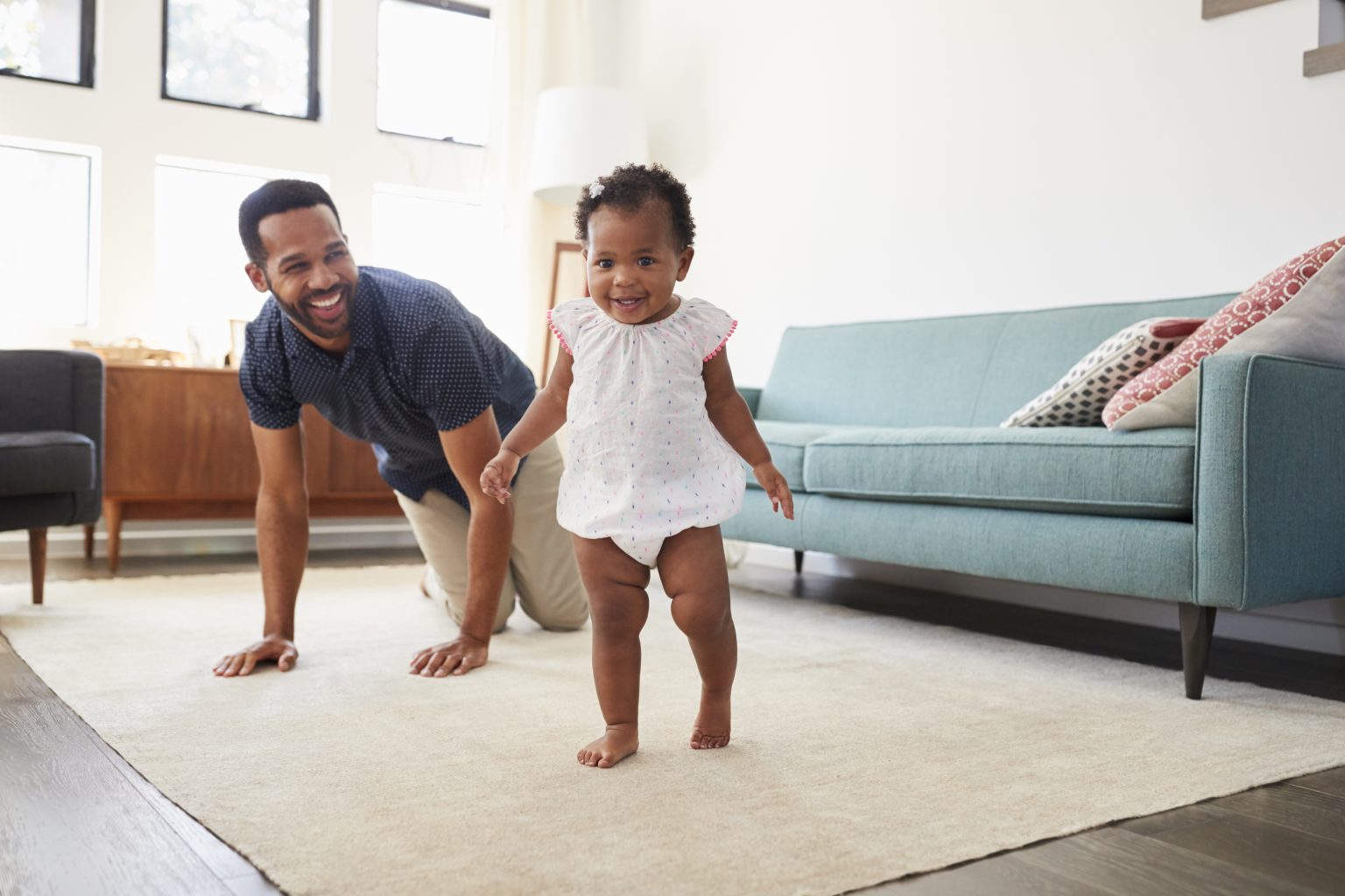GettyImages - dad watching daughter learn to walk