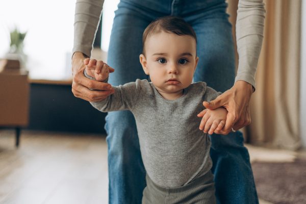 GettyImages - mom helping toddler son walk