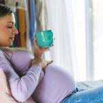 Is it safe to drink caffeine when you’re pregnant? GettyImages- pregnant woman at home with coffee