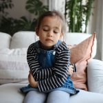 Young girl with stomachache holding her belly