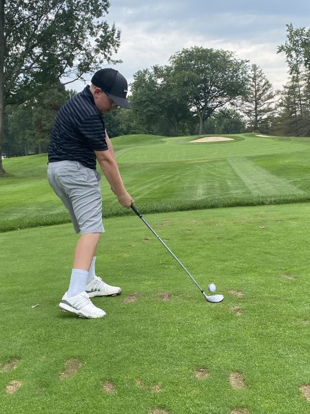 Jake Morrison took up golf at age 5 because his eye disease prohibits him from playing contact sports. He is standing on a golf course, preparing to hit a golf ball in golf attire.