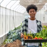 Tips on gut health and probiotics Teen boy holding a container of freshly picked vegetables including carrots, peppers and lettucees