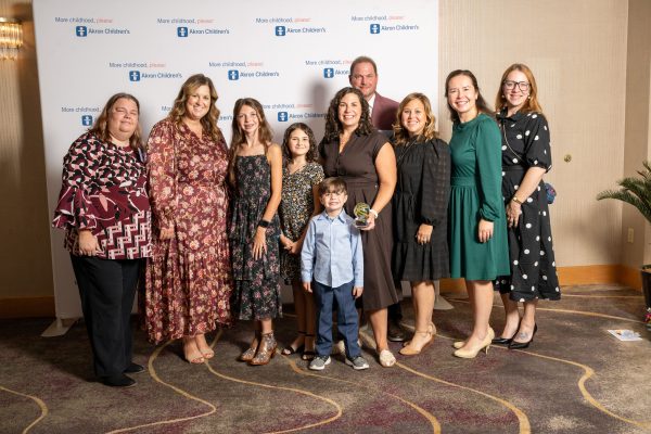 Teresa Fletcher, 2026 Luminary award winner at the Akron Children's "More childhood, please." award ceremony. She is surrounded by a group of family members and colleagues.